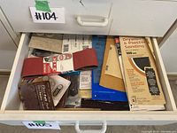 Top drawer with various sanding belts, felt pads, and sandpaper sheets including drywall and plaster sanding sheets.