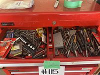 Top drawer of red International toolbox showing assorted screwdriver bits, drill bits, socket bits, and accessories.