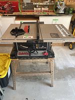 Full view of Delta Sidekick Builders Saw on beige metal stand showing saw top, miter gauge, rip fence, and power cord.