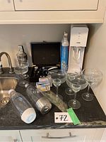 Photo showing all items together on kitchen counter: Sodastream machine, CO2 cylinder, soda bottles, cocktail glasses, cocktail shaker, and accessories.