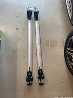 Full view of two aluminum crossbars with black plastic mounts side by side