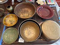 Top view showing entire lot including multiple brass and enameled bowls, ceramic with brass base, and a brass cake pan.