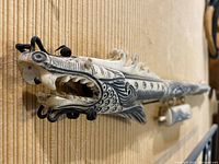 Close-up view of the dragon sculpture's head showing detailed carving, black markings, open mouth with teeth and decorative whiskers.