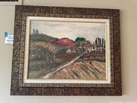 Full view of the framed countryside landscape oil painting showing the entire artwork and the detailed textured brown frame.