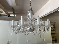 Front angle view of the 10-arm crystal chandelier showing the detailed crystal arms, candle-style bulb holders, and hanging crystal pendants.