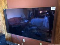 Front view of wall-mounted TV reflecting living room furniture