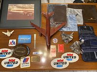 Full overview of airline memorabilia items including framed plane photo, wood airplane model, patches, trays, playing cards, letter opener, bookends, and bags.