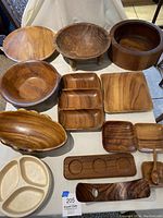 Full view of wooden serving trays and bowls, various shapes and sizes laid on fabric surface.