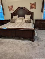 Full view of king size bed frame with ornate tall headboard, curved footboard, and two nightstands flanking the bed.