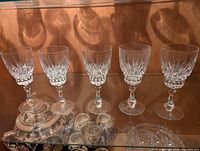 Set of five lead crystal wine glasses with intricate cut detailing, approximately 7 inches tall.