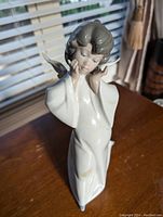Front angled view of Lladró angel figurine showing facial details and glossy finish, placed near window with natural light.