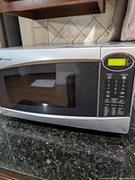 Front view of Silver and black Sharp Carousel microwave oven on granite countertop showing control panel and door with window