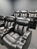 Front and back rows of six black leather home theater seats in a dark room