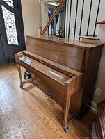 Full view of the upright piano showing wooden finish and general condition.