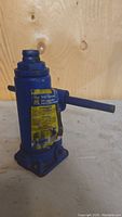 Blue Power Fist 4 ton bottle jack facing front, showing lifting mechanism and label.