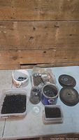Overview of hardware lot containing multiple containers of screws, nails, nuts, bolts, and grinding discs.