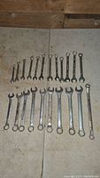 Full set of 23 combination wrenches arranged by size on floor