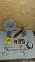 Photo of 12" x 18" dolly on table with coiled aircraft line, yellow caution tape roll, grip grease tool, and pulley accessories
