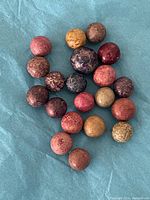 Photo showing 20 colorful clay marbles of various colors and sizes placed on a blue surface.