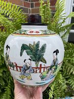 Front view of the ginger jar showing hand-painted scene of children and adults near a fence with banana leaves.