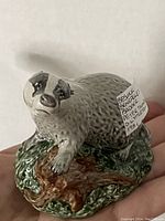 Front and side view of the ceramic badger-shaped decanter with a label describing it as Beswick Beneagles Scotch Whisky Decanter modelled by D. Lyttleton 1981.