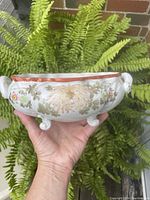 Front view of the oval, hand painted Satsuma planter showing floral patterns and feet.