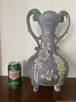 Front side of the large Kutani Moriage vase with visible floral enamel decoration and dragon-shaped handles alongside a soda can for scale.