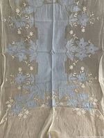 Full view of vintage French country tablecloth with blue floral appliqué on white fabric, showing overall design and size.
