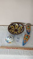 Full view of all four items including large bowl, lidded dish, and two wall hangings, with ruler for scale