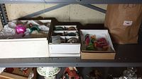 Top shelf with three open boxes containing assorted Christmas ornaments including shiny balls and handcrafted figurines