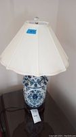 Full view of the blue and white ceramic lamp with cream bell-shaped shade on top, showing overall condition and design.
