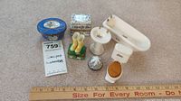 Seven miniature porcelain items including two Limoges boxes and a bathroom set with boots, sink, toilet, and bathtub arranged next to a ruler and lot tag.