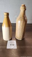 Photo of two old stoneware bottles on wooden surface, showing size and shape