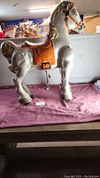 Side view showing the full metal rocking horse with detailed painted saddle and bridle