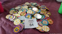 Large pile of circular Simpsons pogs spread on a flat surface showing various character faces and logos