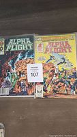 Two Alpha Flight comic books with colorful covers showing multiple characters, placed side by side with a MaxSold lot label.