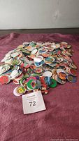 Photo of a large pile of colorful collectible pogs spread out on a purple fabric surface.
