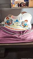 Side view of the Raggedy Ann and Andy rocking horse showing illustrations and rocking base
