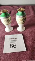 Front view of Japanese porcelain salt and pepper shakers with floral patterns and green/gold tops.