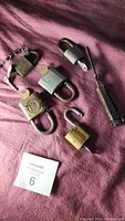 Top down view of six vintage locks including various materials and types placed on purple fabric.