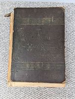 Front cover of the large book showing title and decorative embossing with visible wear and tear, loose binding.