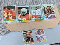 Front view of 7 football cards from 1981 Topps laid out in a row showing players Karl Lorch, Ottis Anderson, Jay Hamilton, Cliff Branch, and others