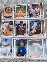 Close-up photo of 9 baseball cards in protective sleeves showing players and a star rookie checklist card.