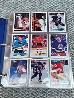 Page of hockey cards in protective sheets inside blue three-ring binder showing a variety of player hockey cards from 1994-95 Topps series.