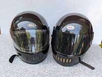 Front view of two black Bell motorcycle helmets side by side, one with clear visor, one with tinted visor.