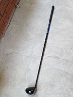 Full length view of the Callaway driver club showing black grip, blue and black shaft and metallic driver head.