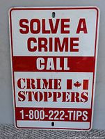 Front view of the metal sign showing red text and Canadian flag on white background.