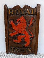 Front view of vintage Royal Tavern bar sign showing the red lion and gold lettering on dark wood-tone background.