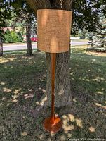 Front view of teak floor lamp including base, shaft, and shade