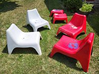 Overview of two white and two red lounge chairs with two red footstools arranged on grass